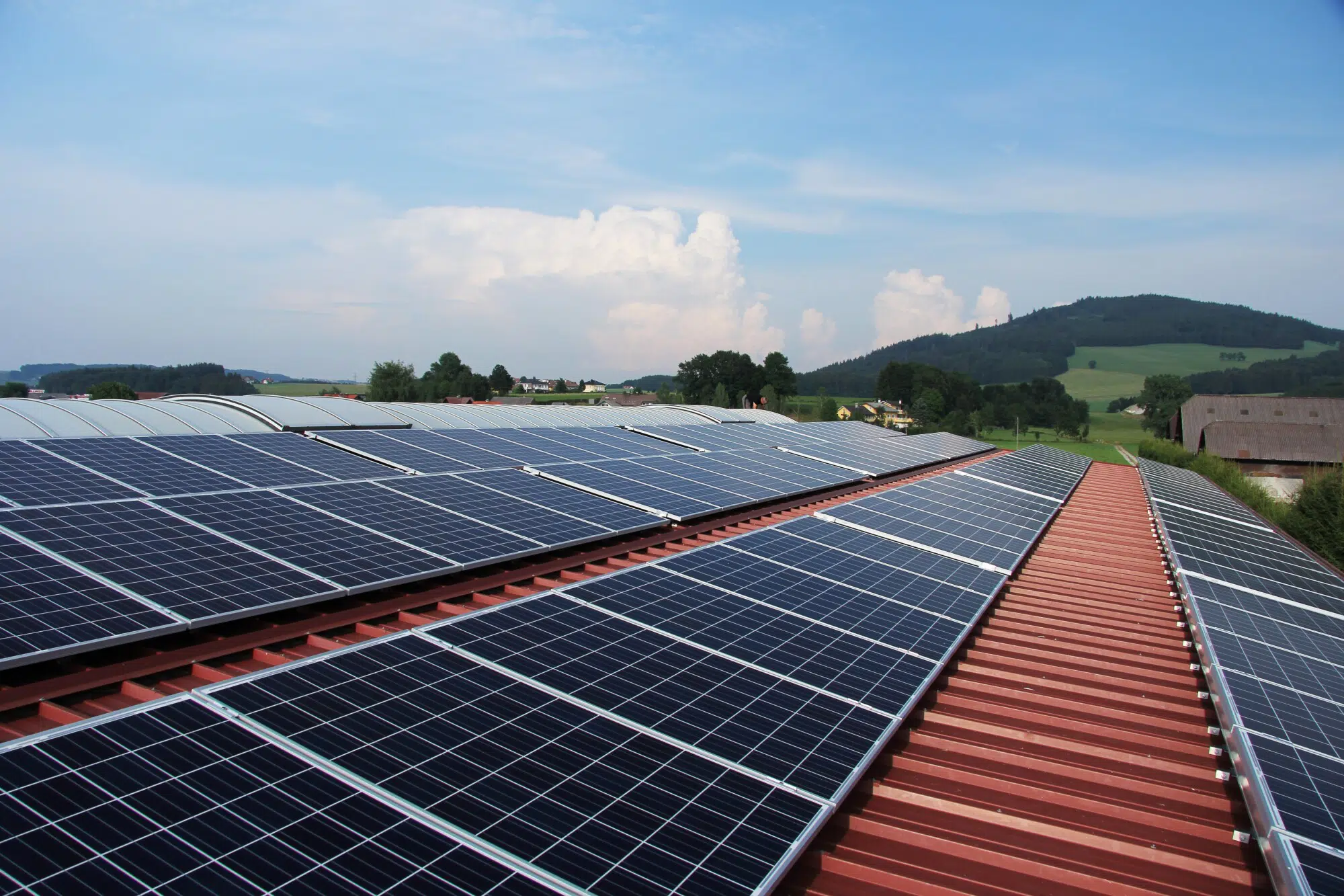 Solar panels on a red metal roof overlooking clear skies